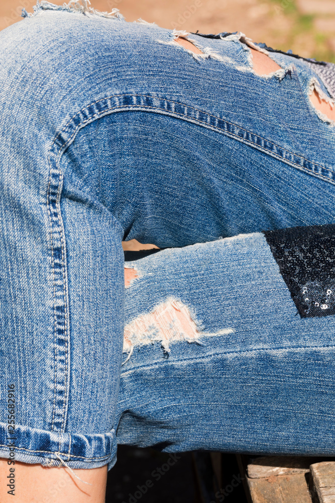 Foto de Gambe incrociate con jeans strappati do Stock | Adobe Stock
