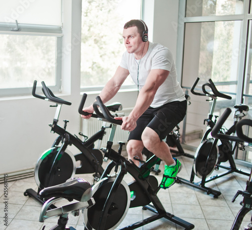 Healthy lifestyle concept. Young sporty man in white t-shirt and shorts is exercising bike at spinning class . Cardio training © splitov27