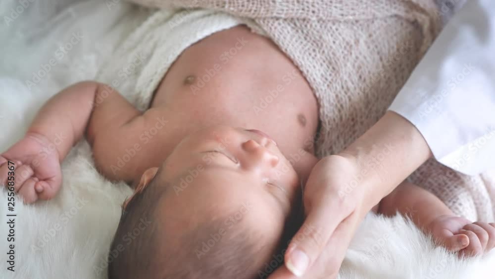 Doctor examining Asian female newborn lying in bed with stethoscope in clinic. Baby health concept Doctor examining Asian female newborn lying in bed with stethoscope in clinic. Baby health concept