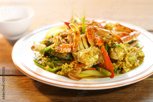 Top view of Fried crab with curry powder, popular seafood menu in asia. Fried crab with curry powder, onion and egg on wooden background. Selective focus, shoot in studio.