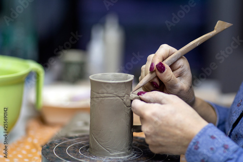Hands of artist who make a mug from ceramic clay in studio