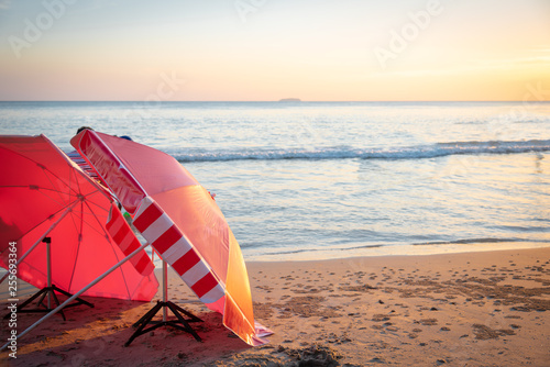 Red umbrella on the beach among  sunset on the sea.