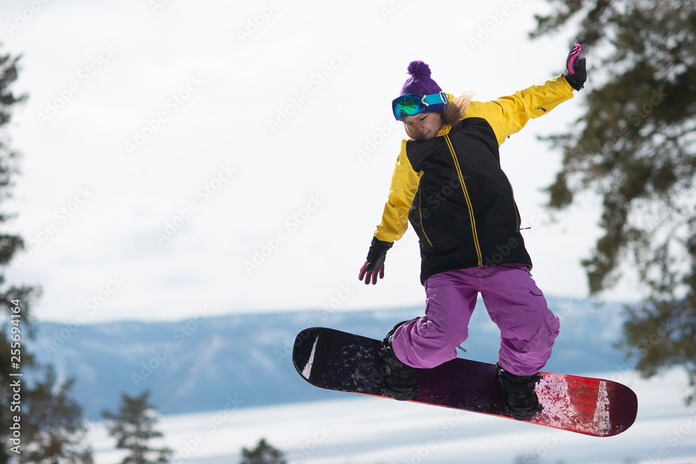 Woman riding a snowboard jumps. Winter sports. Girl in gear on a snowboard