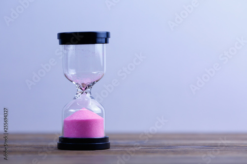 An hourglass on wooden background. Running out of time