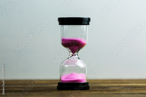 An hourglass on wooden background. Running out of time