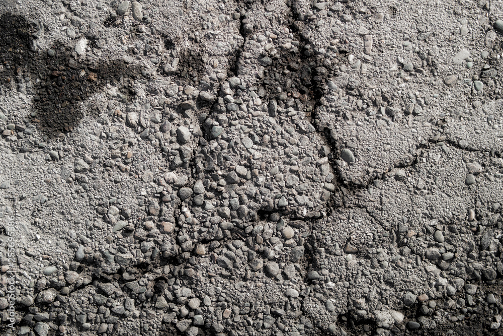 Old road background surface of gray cracked asphalt texture closeup. Old cracked asphalt. Grunge background. Wet Old road background surface of gray cracked asphalt texture closeup. Old cracked asphalt. Grunge background. Wet