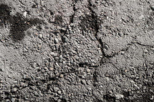 Old road background surface of gray cracked asphalt texture closeup. Old cracked asphalt. Grunge background. Wet