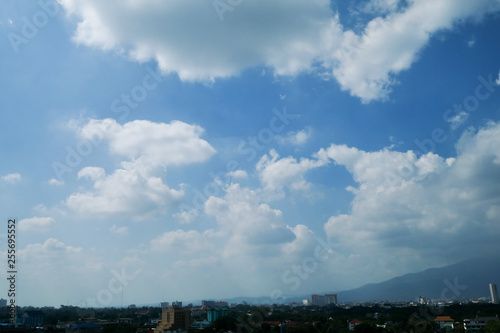 white cloud on clear blue sky above the city skyline © sutichak