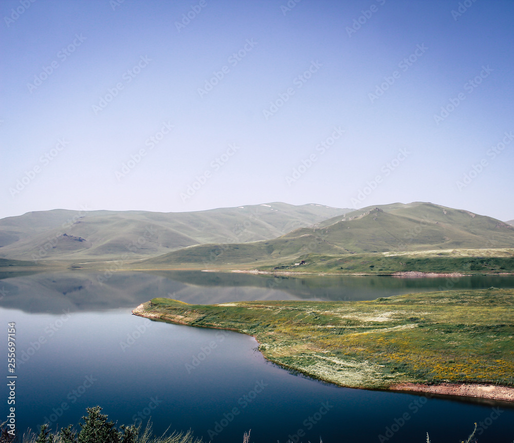 Scenery Lake surrounded by mountains and green fields in Armenia