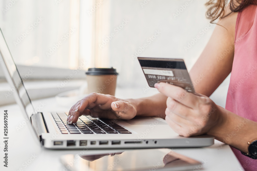 Woman hand holding credit card and using laptop. Businesswoman or entrepreneur working. Online shopping, e-commerce, internet banking, spending money concept Woman hand holding credit card and using laptop. Businesswoman or entrepreneur working. Online shopping, e-commerce, internet banking, spending money concept