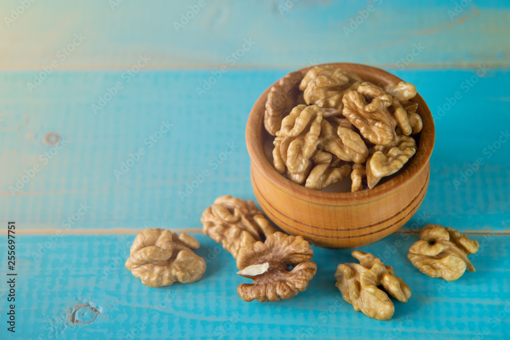 Obraz premium Walnuts on blue rustic table in wooden bowl