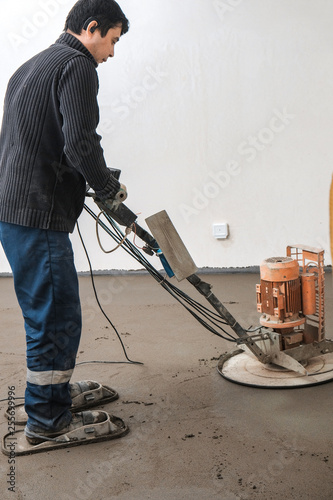 the workers grind the concrete floor at the construction site