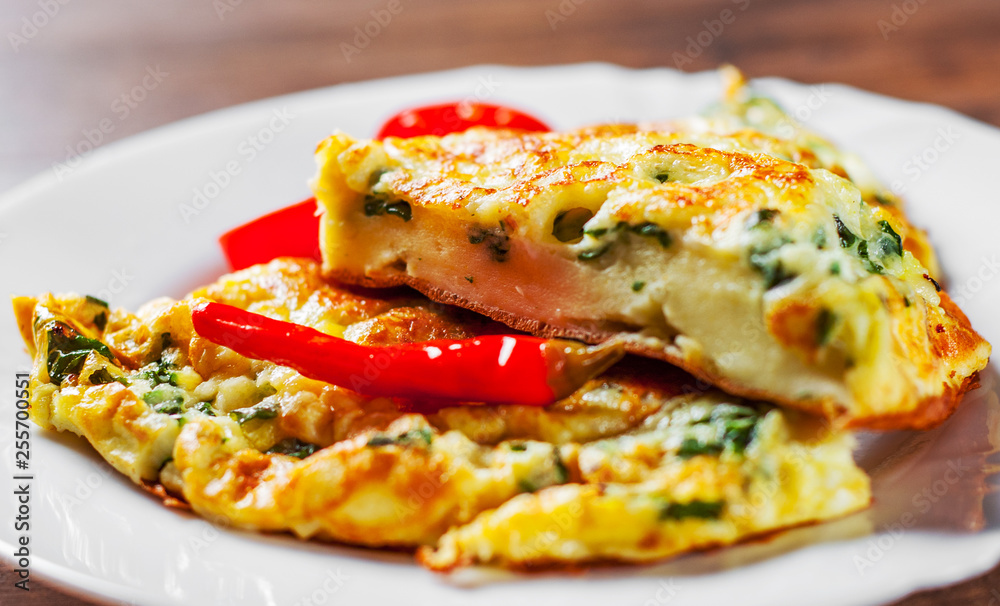omelet with spinach in white plate on wooden table background omelet with spinach in white plate on wooden table background