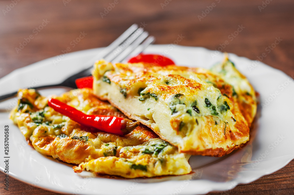 omelet with spinach in white plate on wooden table background omelet with spinach in white plate on wooden table background