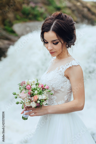 Beautiful portrait of a luxurious bride in nature on the background of a waterfall