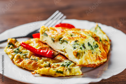omelet with spinach in white plate on wooden table background