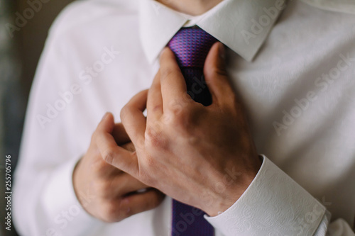 man in shirt dressing up and adjusting tie on neck at home