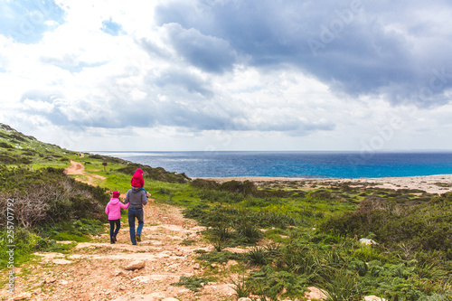 Father and two daughters walk along the path along the sea. Beautiful valley by the sea. Seascape in Cyprus Ayia Napa