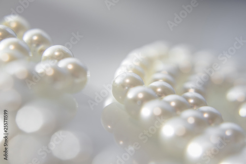 A necklace of pearls lying on white glass 