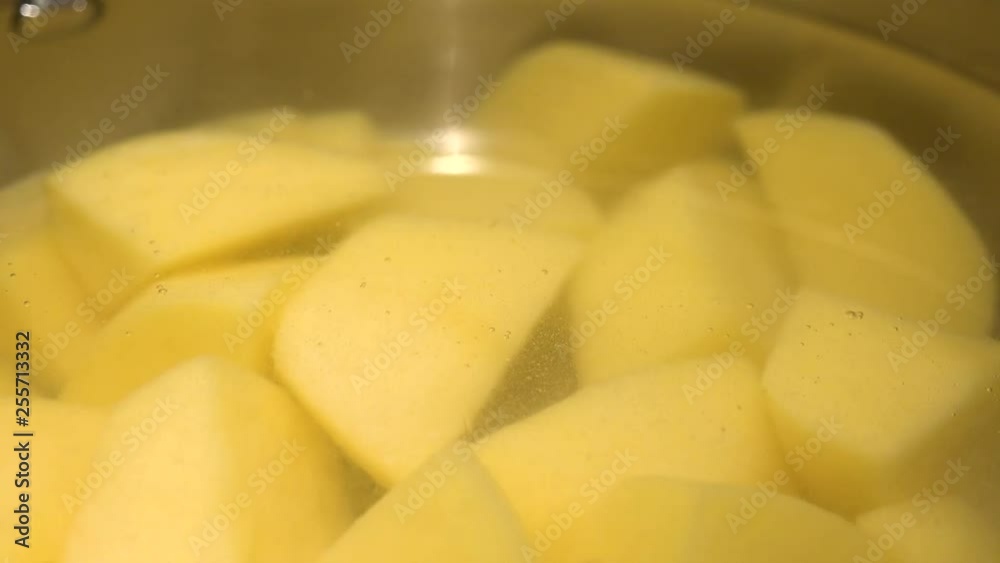 Salt is poured into a pot with water and cut potatoes - closeup Salt is poured into a pot with water and cut potatoes - closeup