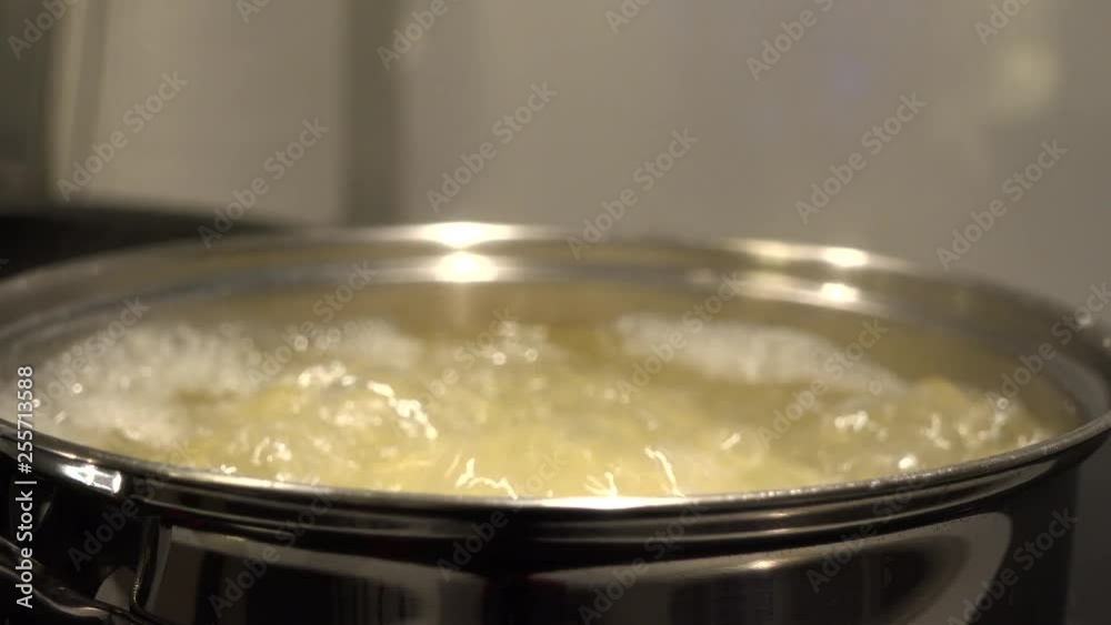 A cover is removed off a pot of potatoes in boiling water in a kitchen - closeup A cover is removed off a pot of potatoes in boiling water in a kitchen - closeup