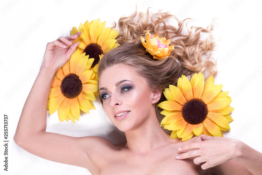 beautiful young woman lying among the flowers of a sunflower