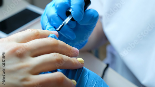 Nail master applies firming nail polish on nails in beauty salon  close-up