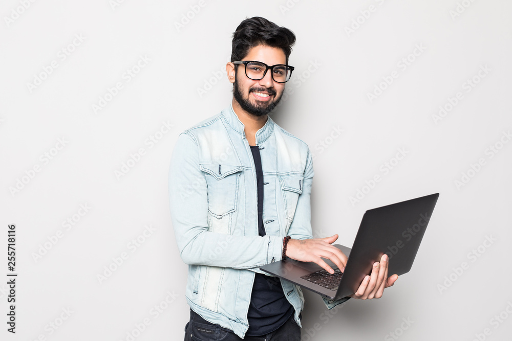 Young indian man looking aside using laptop computer isolated over white background