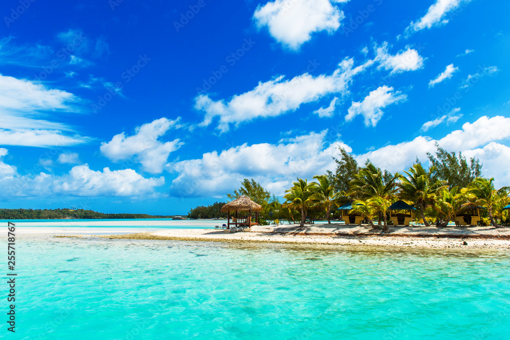 Obraz premium Stunning tropical Aitutaki island with palm trees, white sand, turquoise ocean water and blue sky at Cook Islands, South Pacific. Copy space for text.