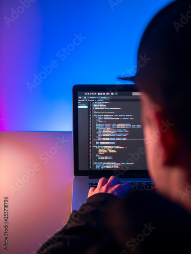 A young guy is a programmer working on a computer in an office. The programmer creates a script for the program or website
