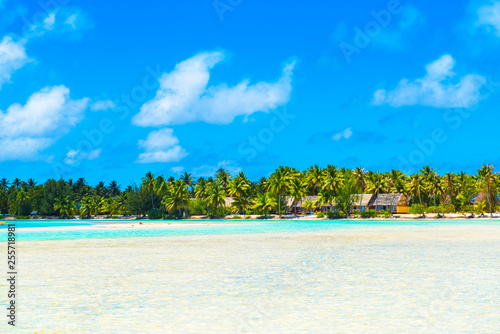 Stunning tropical Aitutaki island with palm trees, white sand, turquoise ocean water and blue sky at Cook Islands, South Pacific. Copy space for text.