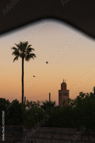 Sunrise / dawn over the roofs of Marrakesh with view of the picturesque and famous Koutoubia Mosque with red glooming sky (Marrakesh, Morocco, Africa)