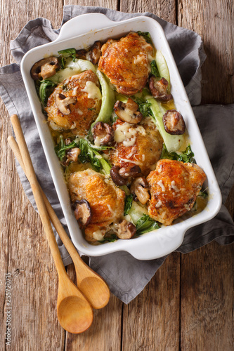 chicken thighs with baby bok choy, shiitake mushrooms and cheese sauce in a rustic style close-up. vertical top view