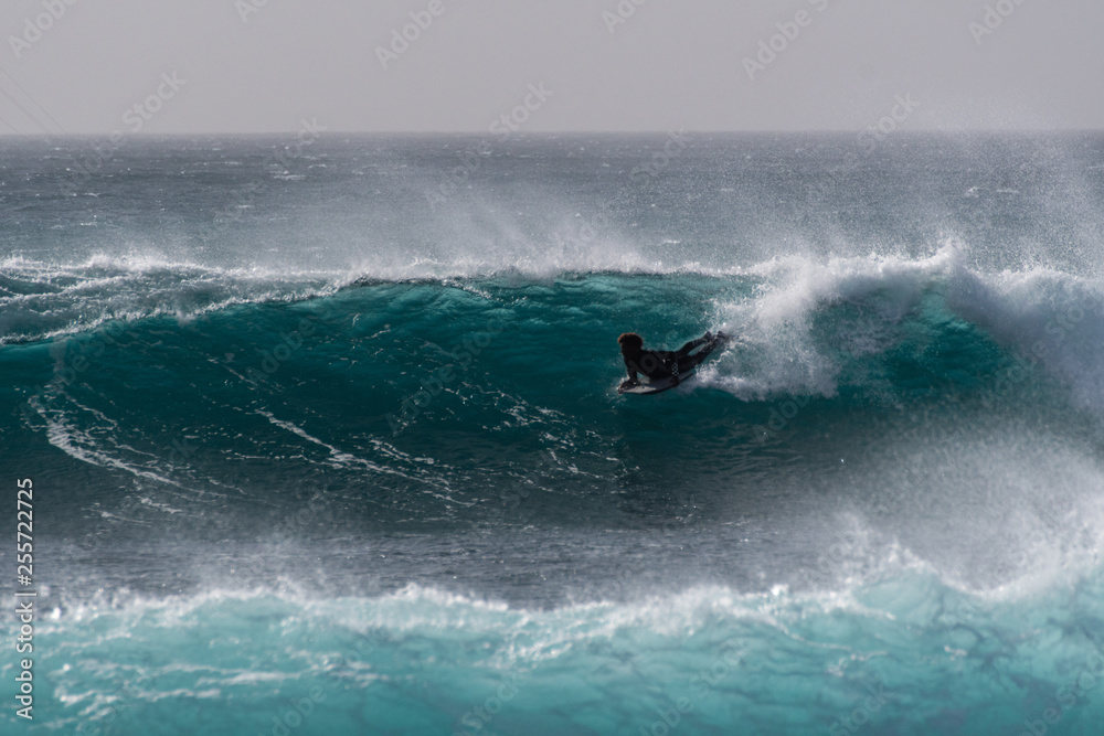 surfer against a deep blue wave 