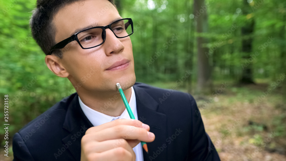 Pensive man thinking about new eco-friendly start up idea, sitting in forest Pensive man thinking about new eco-friendly start up idea, sitting in forest