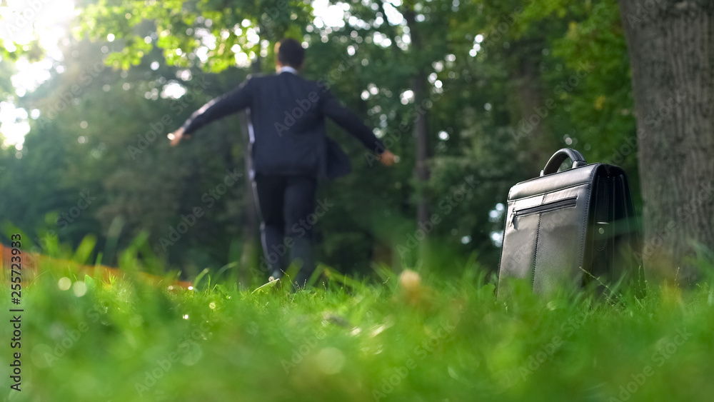 Man in suit leaving his case on grass and happily running into forest, freedom Man in suit leaving his case on grass and happily running into forest, freedom