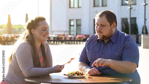 Fat couple eating fresh vegetable salad at outdoor date, health care, calories
