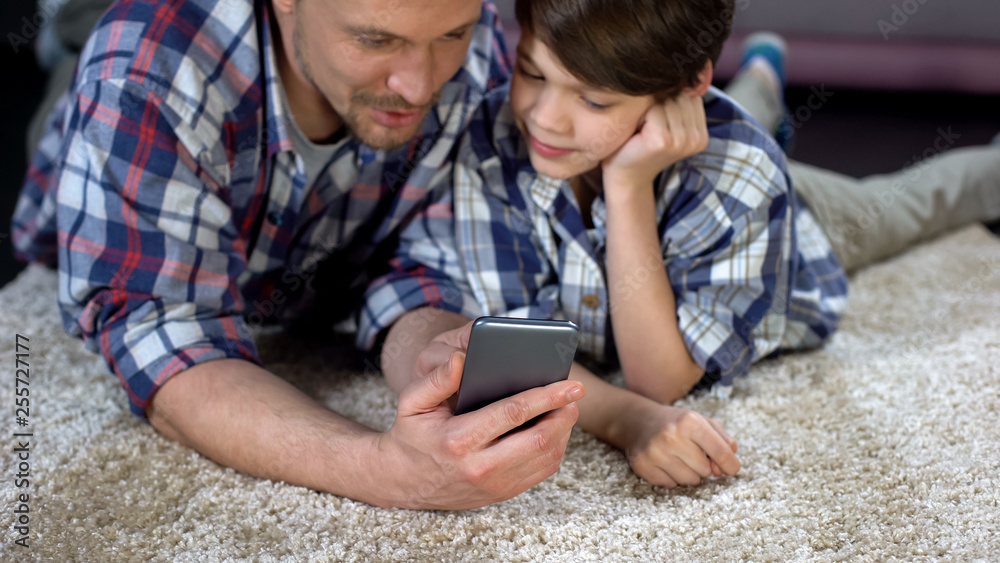 Father showing son funny application on smartphone, spending time together