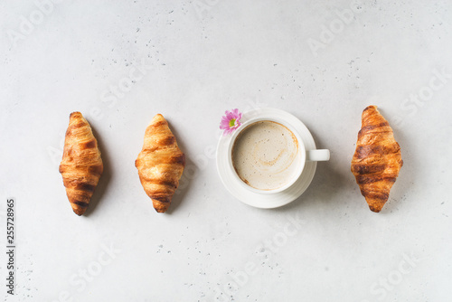 Breakfast concept with cup of coffee, croissants and flower on white background