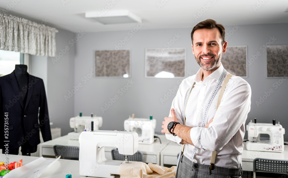 Smiling tailor shop owner standing above workshop desk, fashion design business Smiling tailor shop owner standing above workshop desk, fashion design business