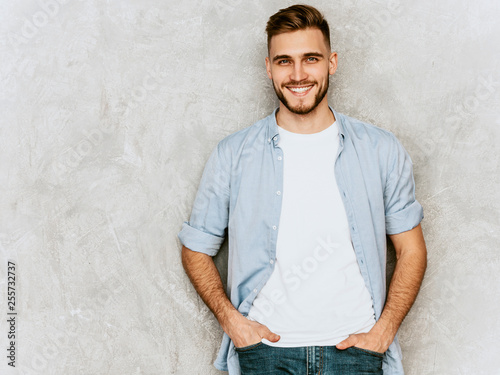 Portrait of handsome smiling hipster lumbersexual businessman model wearing casual shirt clothes. Fashion stylish man posing against gray wall
