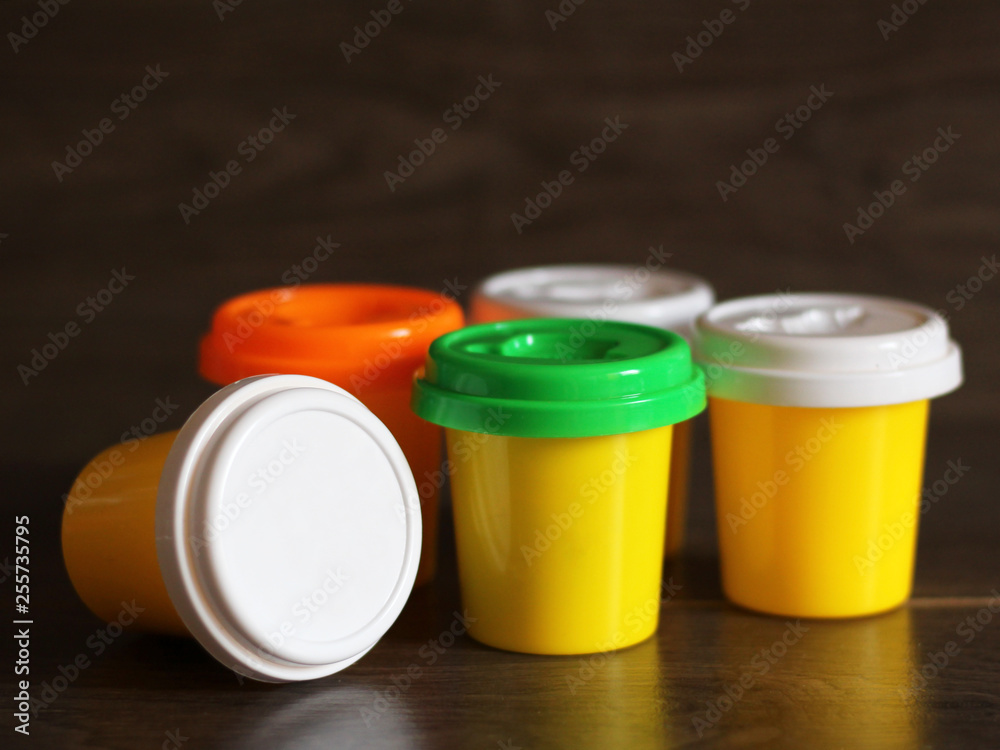 Yellow plastic bottles with colorful lids on wooden background Yellow plastic bottles with colorful lids on wooden background