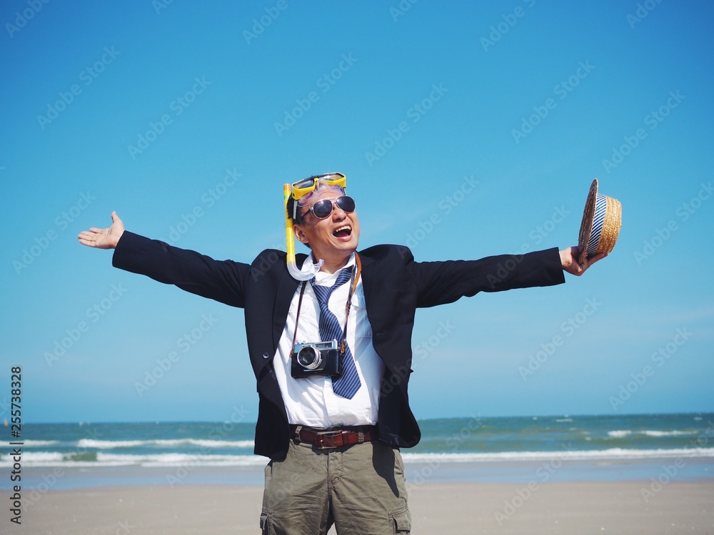 Happy Senior business man standing on the tropical beach,traveler summer concept.