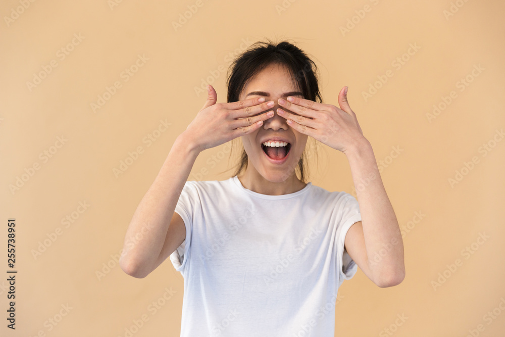 Image of content chinese woman wearing basic t-shirt covering her eyes with hands Image of content chinese woman wearing basic t-shirt covering her eyes with hands