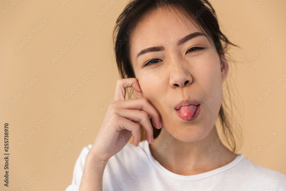 Photo of optimistic korean woman wearing basic t-shirt sticking out her tongue and looking at camera Photo of optimistic korean woman wearing basic t-shirt sticking out her tongue and looking at camera
