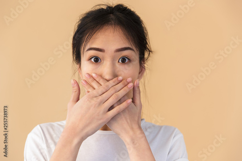 Image of silent chinese woman wearing basic t-shirt covering her mouth with hands