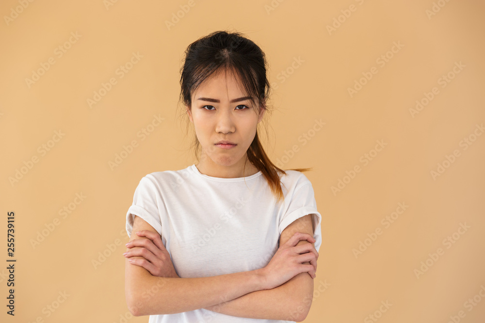 Portrait of outraged asian woman wearing basic t-shirt posing at camera with angry look Portrait of outraged asian woman wearing basic t-shirt posing at camera with angry look