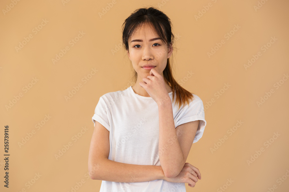 Portrait of brunette asian woman wearing basic t-shirt smiling and looking at camera Portrait of brunette asian woman wearing basic t-shirt smiling and looking at camera
