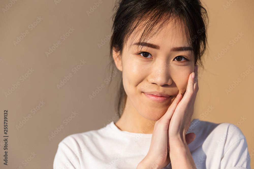 Portrait closeup of charming chinese woman wearing basic t-shirt smiling and looking at camera Portrait closeup of charming chinese woman wearing basic t-shirt smiling and looking at camera