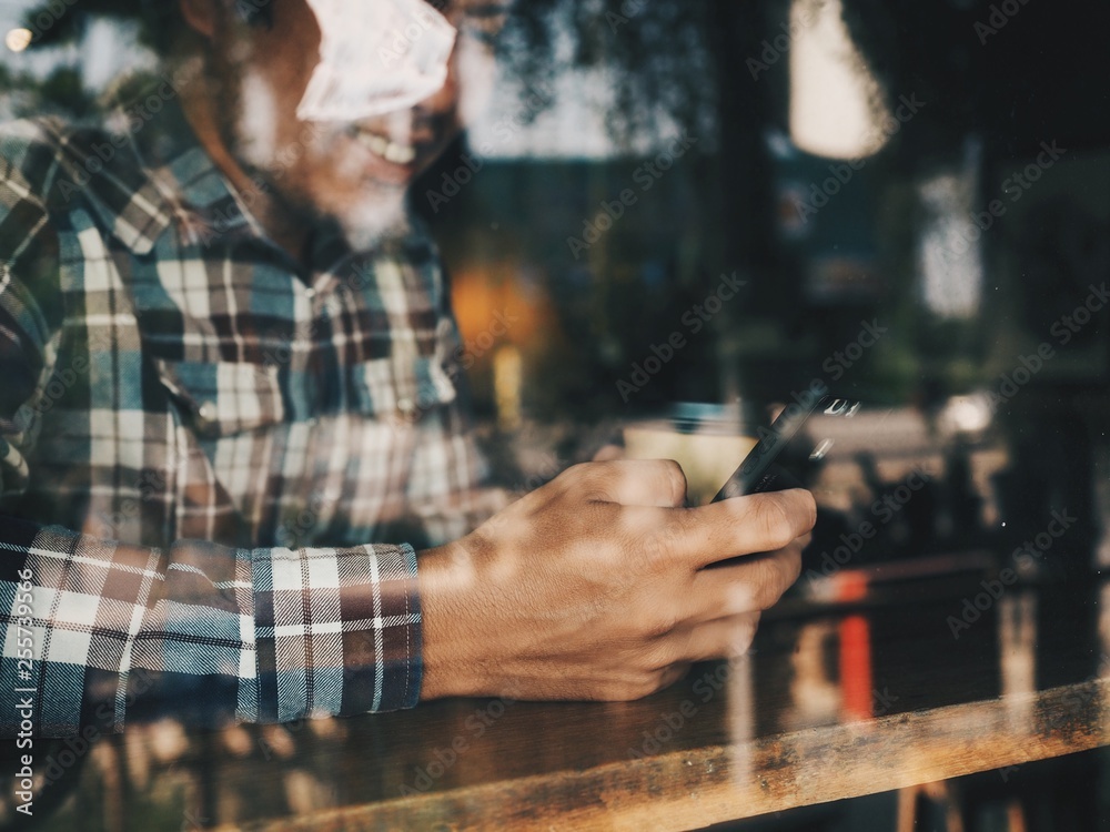 Cropped Asian man hands holding smart phone and coffee cup in cafe. Cropped Asian man hands holding smart phone and coffee cup in cafe.